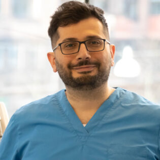 Hussein, known as Hosse, dental hygienist at Gloss & Floss in Stockholm, wearing blue scrubs at the clinic.