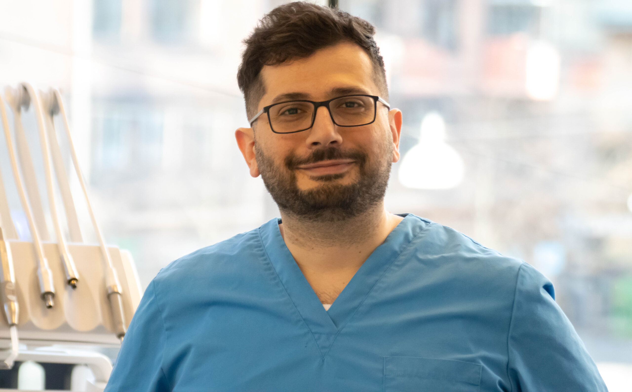 Hussein, known as Hosse, dental hygienist at Gloss & Floss in Stockholm, wearing blue scrubs at the clinic.